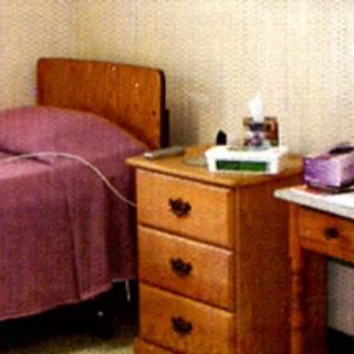 A simple bedroom setup with a bed, side table, and desk.
