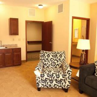 A cozy living room with a patterned armchair, sofa, and warm lighting.