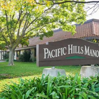 Entrance sign of Pacific Hills Manor surrounded by greenery.