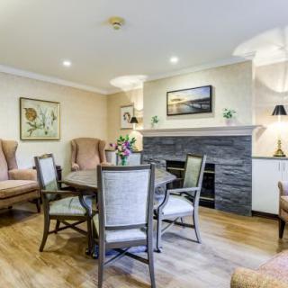 A cozy living room featuring a dining table with chairs, armchairs, a fireplace, and elegant decor.