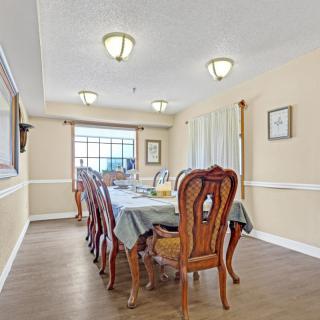 A spacious dining room with a long table set for a meal, surrounded by elegant wooden chairs and illuminated by ceiling lights.