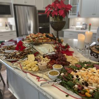 A beautifully arranged charcuterie and cheese board set up in a festive kitchen.