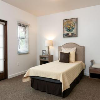 A cozy bedroom with a single bed, nightstand, and framed artwork.