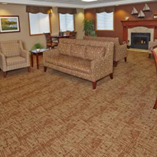 A cozy living room interior with sofas, chairs, a fireplace, and carpeted flooring.