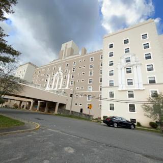 A view of a multi-story hospital building under a partially cloudy sky.