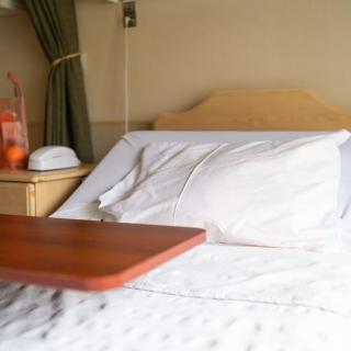 A hospital bed with a bedside table and medical equipment in a patient room.