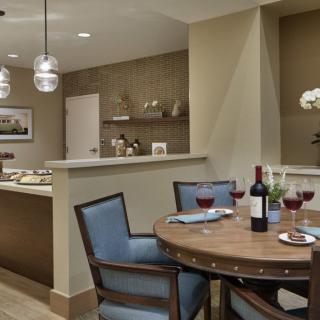 A cozy dining area with a round table set for dinner, featuring wine glasses and ambient lighting.