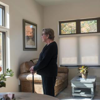 A woman stands by the window, enjoying the natural light in a cozy living space.