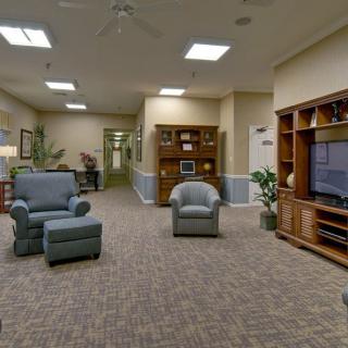 A cozy living room with armchairs, a large television, and bookshelves.