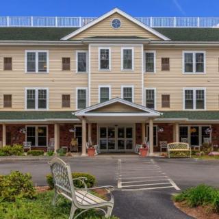A three-story residential building with a landscaped entrance and benches.