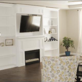 A cozy living room featuring a mounted television above a fireplace, surrounded by built-in bookshelves and tasteful decor.