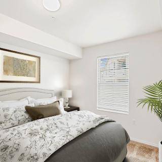 A modern and inviting bedroom featuring soft colors, elegant decor, and a touch of greenery.