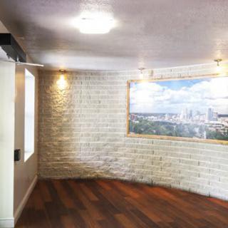 A modern room with a brick wall and wood flooring, featuring artwork and soft lighting.