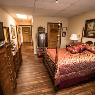 A cozy bedroom featuring a wooden bed, decorative artwork, and warm lighting.
