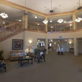 A spacious lobby with a staircase, seating area, and warm lighting.