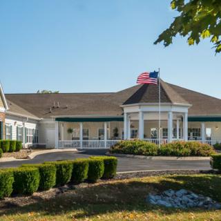 A well-maintained single-story building with an American flag flying, surrounded by manicured landscaping.