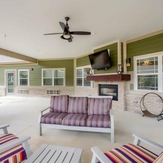 A spacious covered patio with comfortable seating, a fireplace, and a mounted television.