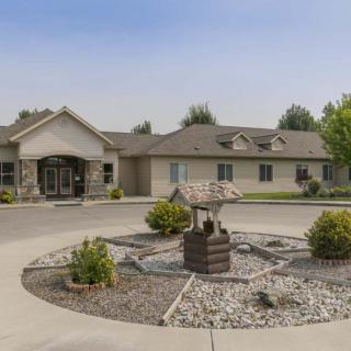 A single-story building with a circular driveway and landscaped garden in the front.