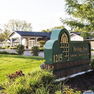 A lush, green landscape surrounds a building with a prominent entrance sign displaying the address 1215.