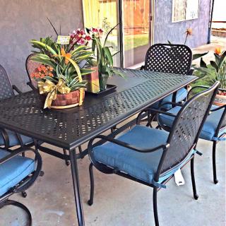 A stylish outdoor patio set featuring a metal table and chairs adorned with potted plants.