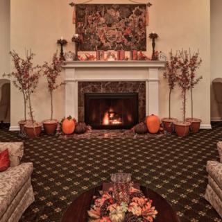 A cozy living room with a decorated fireplace, featuring autumn-themed decor and pumpkins.