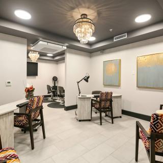 A modern nail salon interior with decorative chandeliers and colorful artwork.
