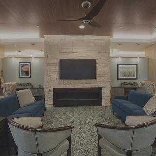 A modern living room with comfortable seating, a central fireplace, and a television mounted on the wall.