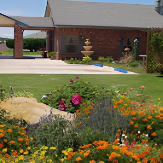 A charming brick house with a vibrant garden and fountain in the yard.