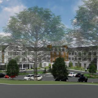 A residential apartment complex surrounded by trees with cars parked in the lot.