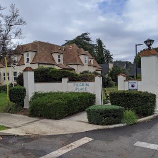 A charming residential entrance with well-maintained landscaping under a cloudy sky.