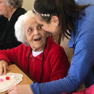 A joyful moment between a caregiver and an elderly woman during a community activity.