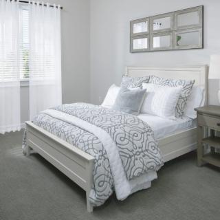 A neatly decorated bedroom with a white bed and patterned bedding.