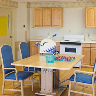 A kitchen area with a table and chairs, featuring an oven and other small appliances.