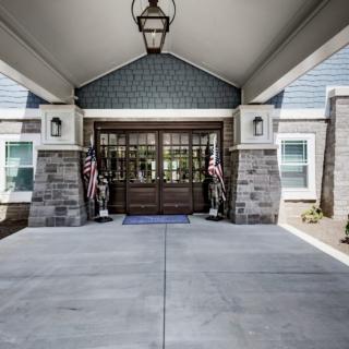 A covered entrance of a building with American flags flanking the doorway.