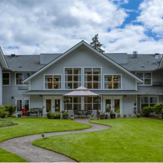 A spacious two-story house with a well-maintained lawn and a cloudy sky backdrop.