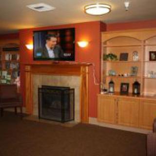 A cozy living room featuring a fireplace, television, and built-in shelves with decor items.