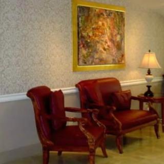 A cozy lobby area with red chairs, a lamp, and abstract artwork on the wall.