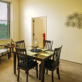 A cozy dining room featuring a table with four chairs and wall decor.