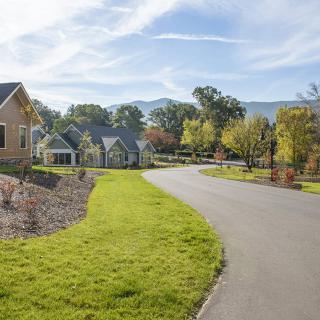 A suburban neighborhood with houses lining a winding road under a clear blue sky.