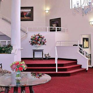 Elegant interior with a red-carpeted staircase and floral decorations.