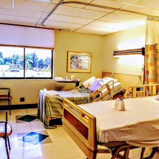 A serene hospital patient room with two beds, a window letting in natural light, and a calming atmosphere.