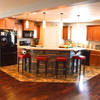 A modern kitchen with a central island, surrounded by bar stools and illuminated by pendant lights.