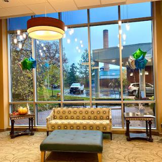 A stylish lobby featuring a comfortable seating area, large windows allowing natural light, and modern lighting fixtures.