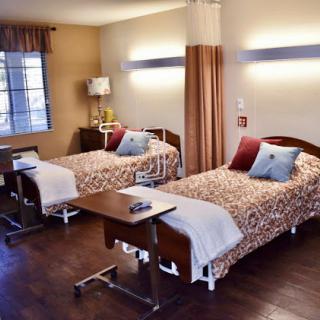 A cozy hospital room featuring two beds with patterned blankets, designed for patient comfort.