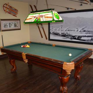 A billiard table in a vintage-themed recreation room with wooden flooring and wall decorations.