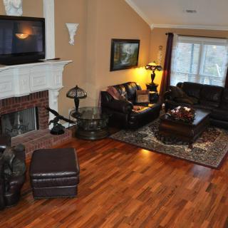 A cozy living room with hardwood floors, a fireplace, and comfortable seating.