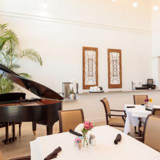 A stylish restaurant interior featuring a grand piano and elegantly set tables.