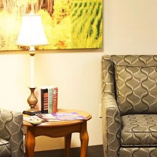 A cozy living room corner with a patterned chair, side table, and lamp.