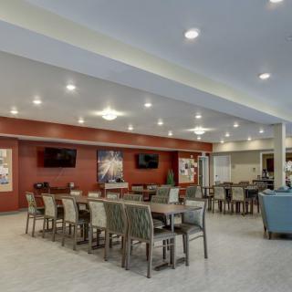 A modern dining area with neatly arranged tables and chairs, featuring bright lighting and a warm ambiance.