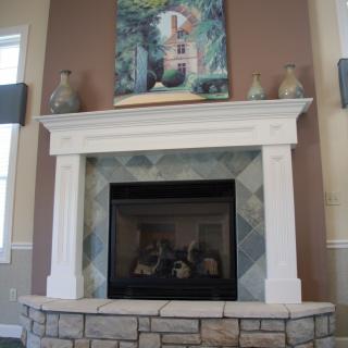A stylish fireplace with a stone surround and decorative mantel, featuring artwork and vases.